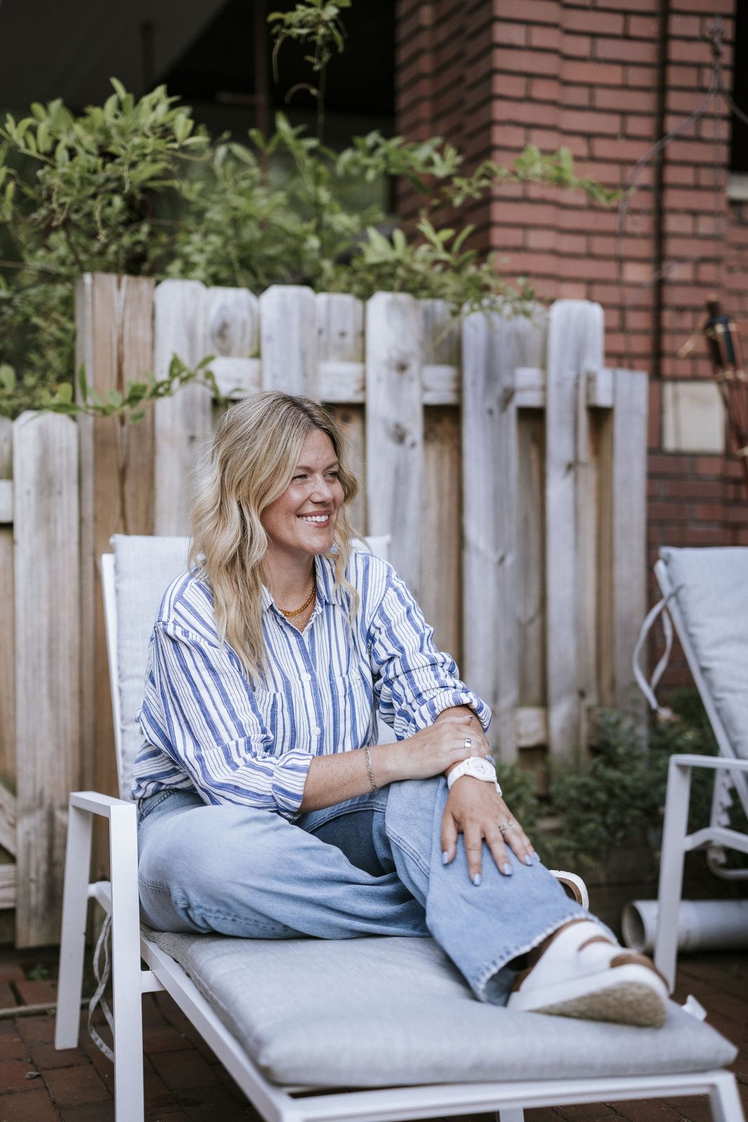 woman smilign sitting on lawn chair on deck on sunny day